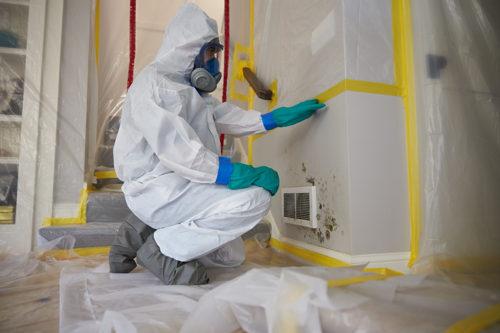 Technician in protective gear inspecting an affected area
