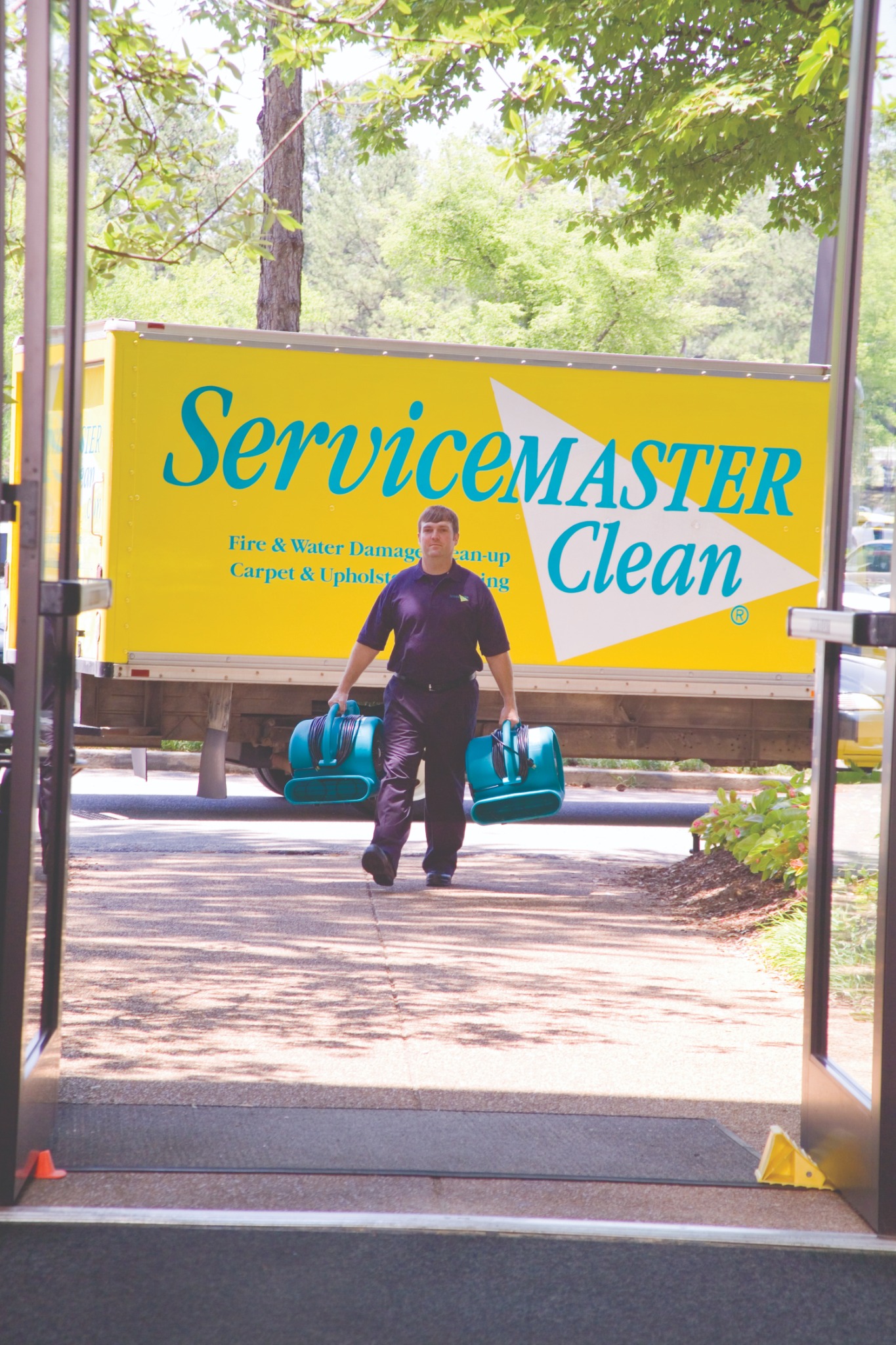 ServiceMaster technician carrying drying equipment